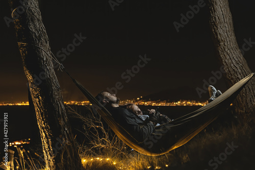 Couple relaxing in a hammock and enjoying starry sky. View from the top of the mountain to the lights of the city of Naples. Volcano Vesuvio. Sea and romance. Sorrento Italy photo