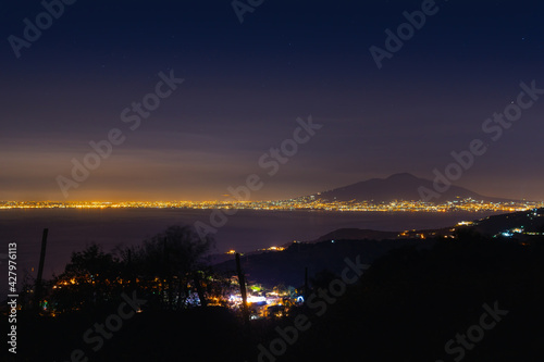 Mount Vesuvius and the lights of the city of Naples from a great distance. Night view. Space to insert text. Sea and tranquility Tourism