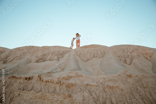 Woman being kissed by her loving son during sunset. Mother with her son on sand dune.