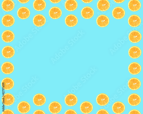 Summer pattern made of slices of orange on a light blue cyan background. Space for a message