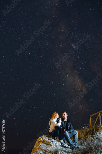 Couple traveler enjoying watched the star and milky way galaxy over the sky on top of the mountain. Night landscape with beautiful sky. Vertical photo