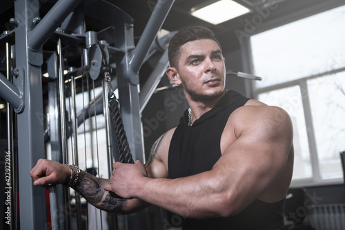 Attractive muscular sportsman resting at the gym, looking away thoughtfully