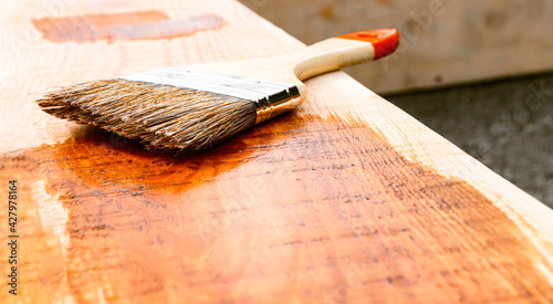 Painting wood with a brush and paint and varnish materials in an open area. Small business, woodworking.