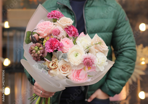 Wallpaper Mural Strong man holding a delicate bouquet of beautiful flowers in his hands. Delicate flower bouquet. Wrapped flowers bouquet. Fresh beautiful flower. Man holding a big beautiful flowers bouquet. Torontodigital.ca