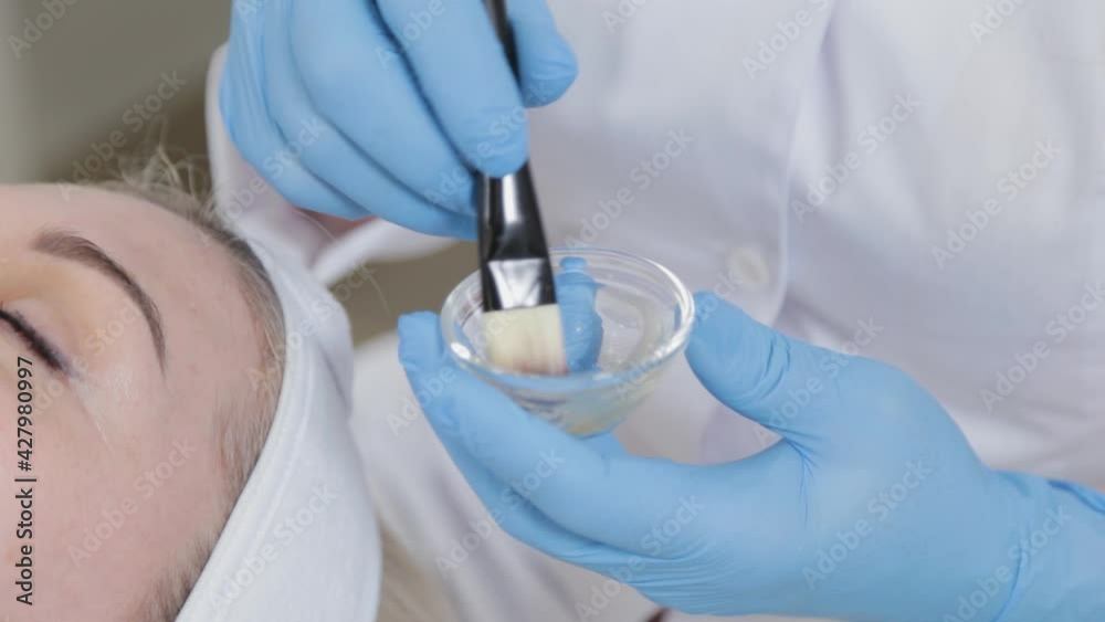 Professional beautician woman applying mask on face with brush to client. Professional beautician woman applying mask on face with brush to client.