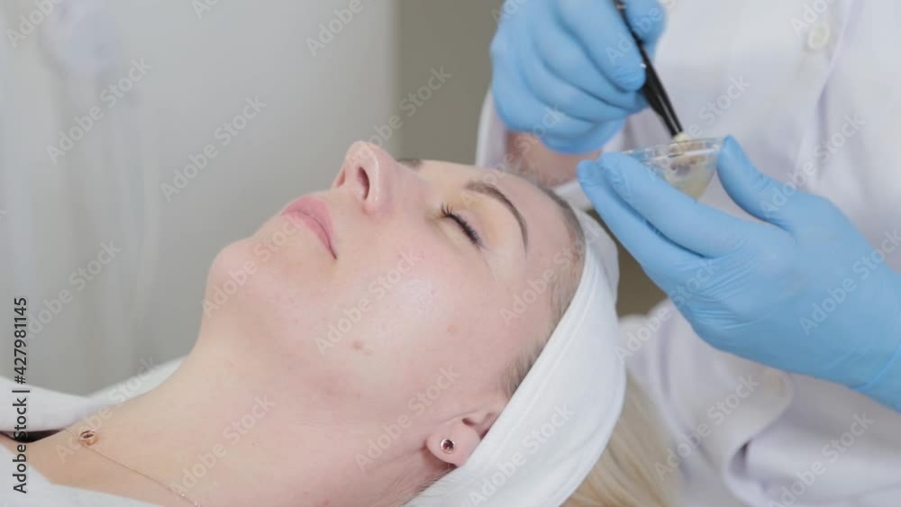 Professional beautician woman applying mask on face with brush to client. Professional beautician woman applying mask on face with brush to client.