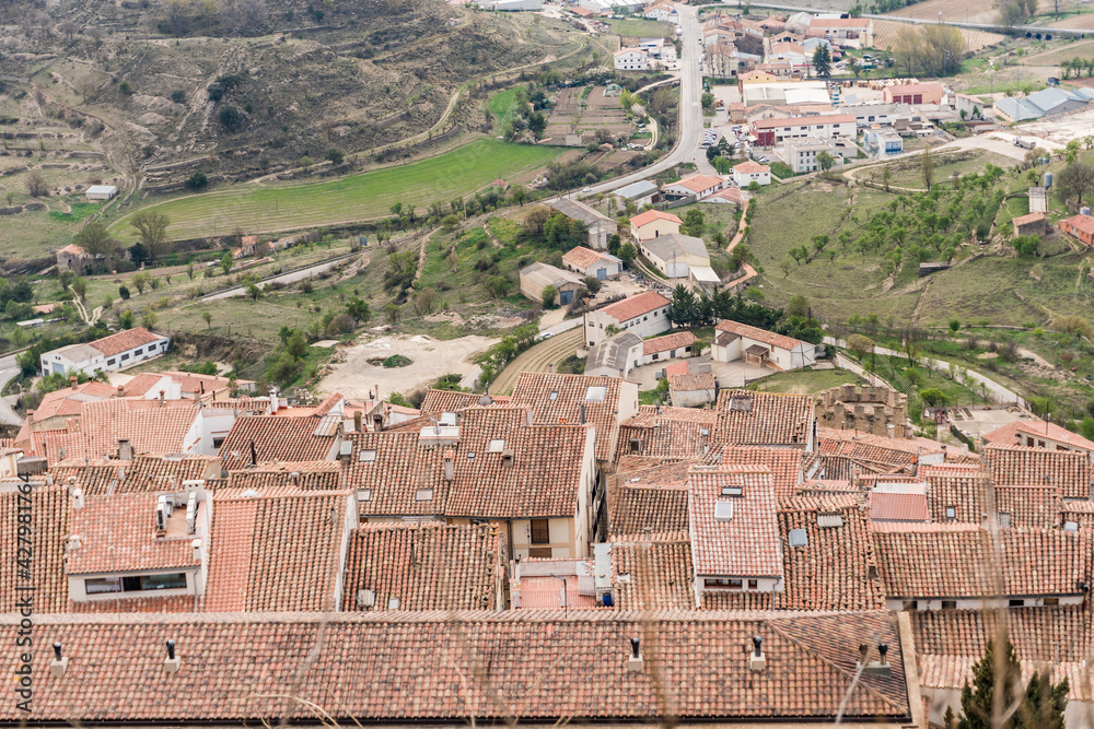 Red clay tile roofs in different heights and skylights and chimneys, with the driveway and surrounding fields, cultivation terraces with green grass and trees.