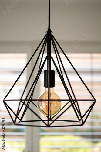 Black minimalist lamp in interior. Loft lamps, vintage, retro, scandi style. Edison's light bulb with warm tone light. © violettaviovi
