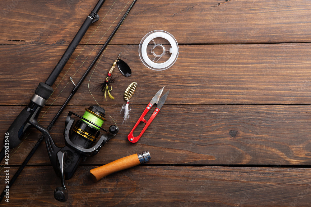Fishing tackle - fishing spinning rod, hooks and lures on wooden background. Active hobby recreation concept. Fishing tackle - fishing spinning rod, hooks and lures on wooden background. Active hobby recreation concept.