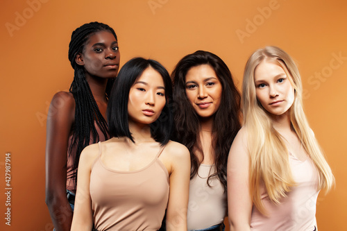 young pretty asian, caucasian, afro woman posing cheerful together on brown background, lifestyle diverse nationality people concept © iordani