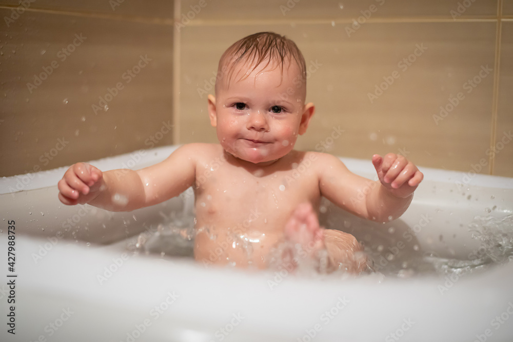 Little charming girl babe plays in the water in small inflatable baby pool located in the shower stall in bathroom, baby girl smiling and having fun Little charming girl babe plays in the water in small inflatable baby pool located in the shower stall in bathroom, baby girl smiling and having fun