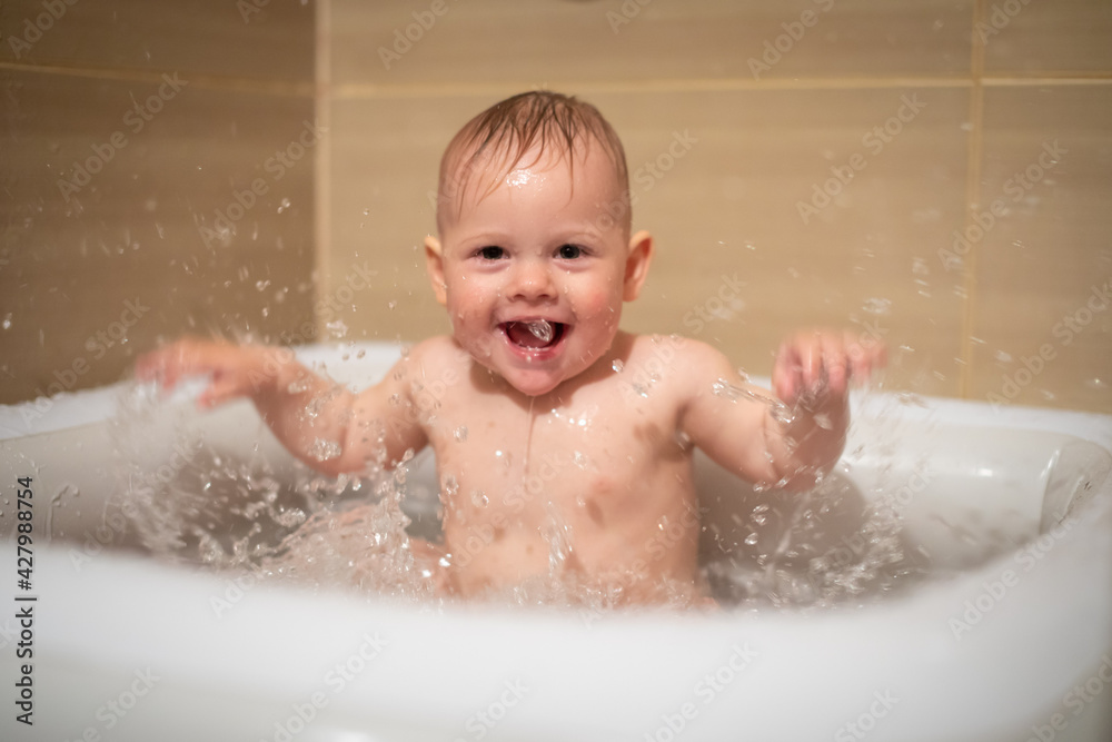 Little charming girl babe plays in the water in small inflatable baby pool located in the shower stall in bathroom, baby girl smiling and having fun Little charming girl babe plays in the water in small inflatable baby pool located in the shower stall in bathroom, baby girl smiling and having fun