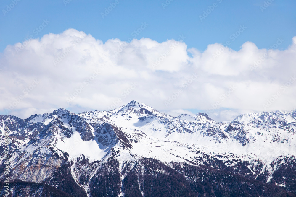 Winter landscape, snowcapped mountains with cloudscape, blue sky. Snowy mountain peaks in Swiss alps, Wallis.