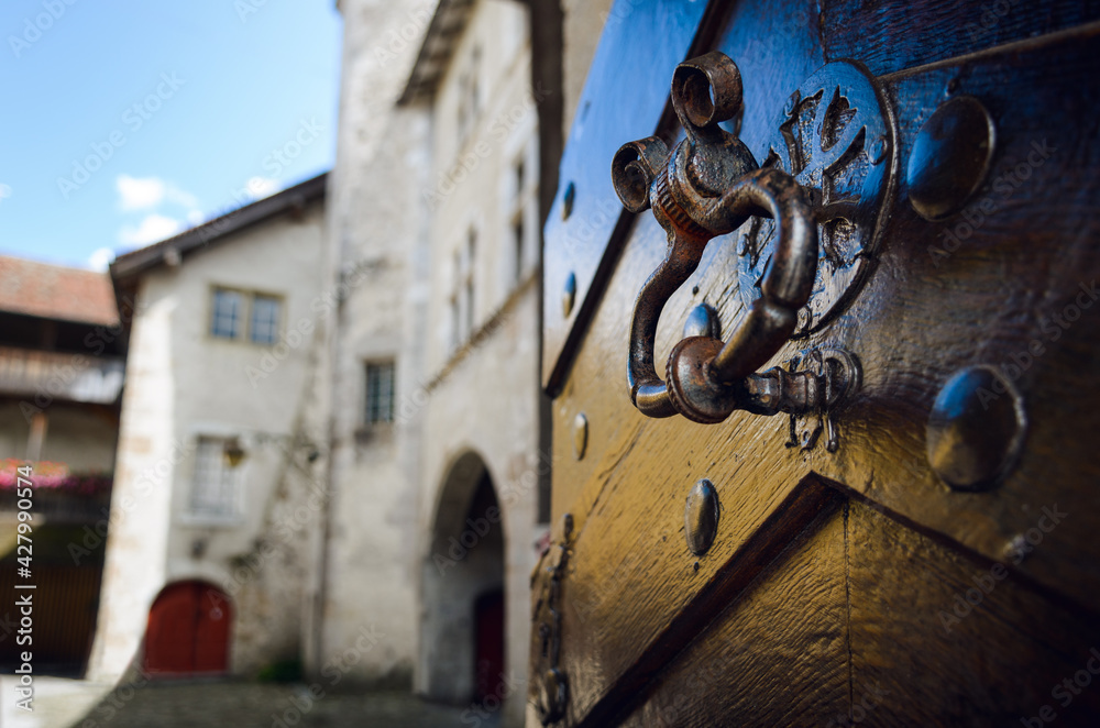 Ancient ring shaped metal knocker on a wooden studded door with signs of aging and weather Ancient ring shaped metal knocker on a wooden studded door with signs of aging and weather