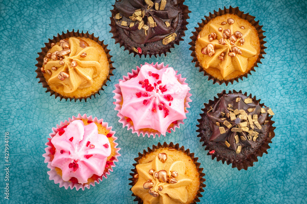 several luxurious strawberry, coffee and chocolate cupcakes with chocolate and golden sprinkles