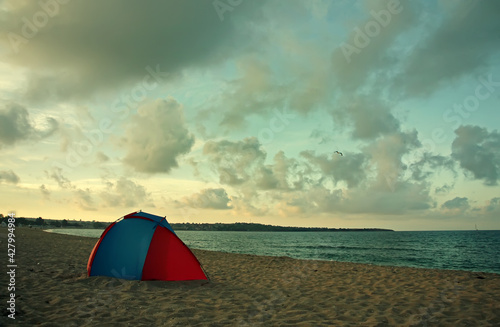 Lonely tent on the beach near the sea at summer evening