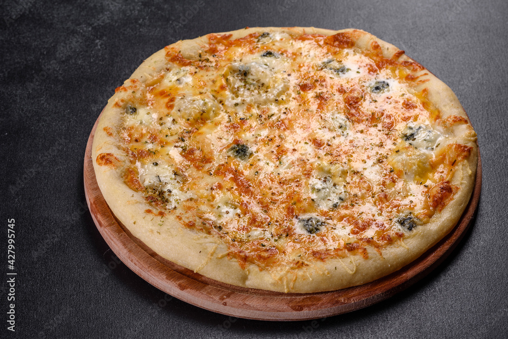 Tasty fresh oven pizza with tomatoes, cheese and mushrooms on a dark concrete background