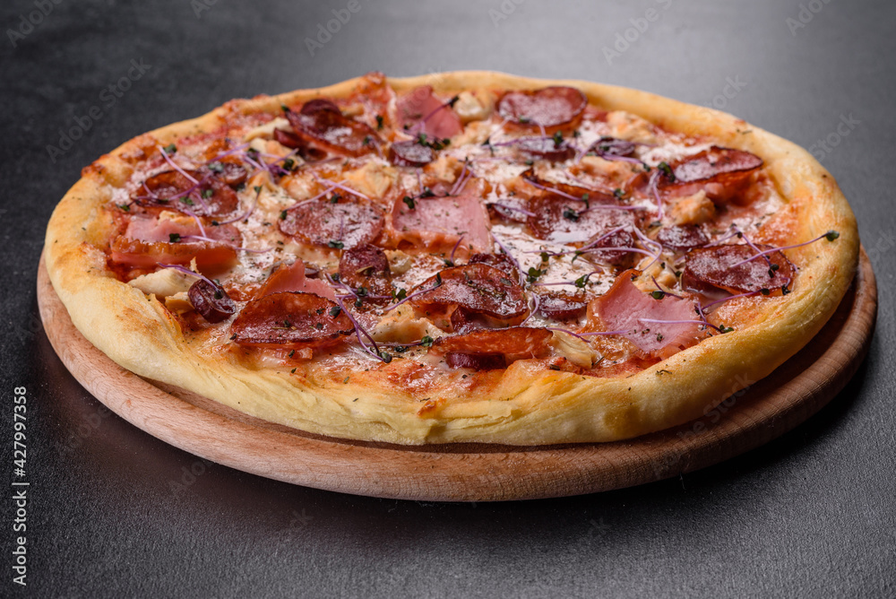 Delicious fresh oven pizza with tomatoes, salami and bacon on a dark concrete background Delicious fresh oven pizza with tomatoes, salami and bacon on a dark concrete background