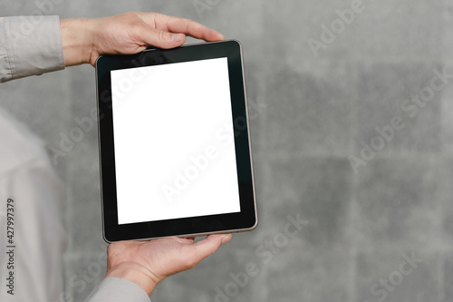 Close up, mock up tablet, in hands, of a person. against the background of a concrete wall.