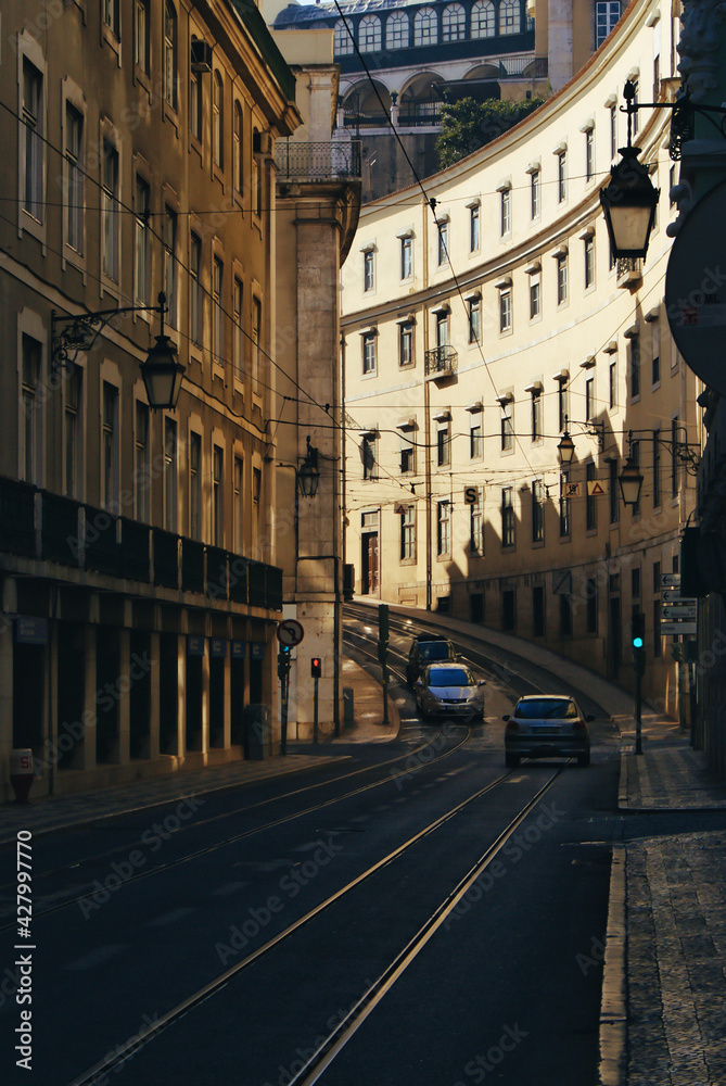 A street in Lisbon, Portugal.
Cars and lines for the trolleybus. Curved buildings and sunset light.