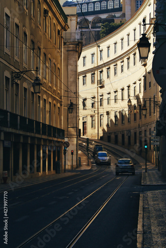 A street in Lisbon, Portugal. Cars and lines for the trolleybus. Curved buildings and sunset light. © Pier Fax