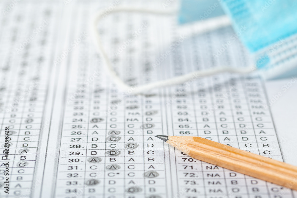 testing in exercise and examination work. blue medical mask, sheet with pencil in school test room, education concept during pandemic testing in exercise and examination work. blue medical mask, sheet with pencil in school test room, education concept during pandemic