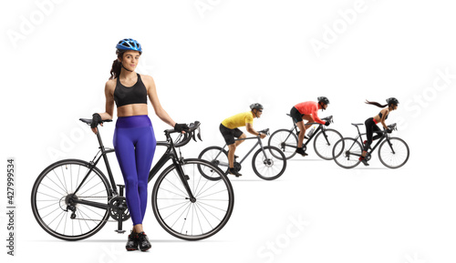 Fototapeta Naklejka Na Ścianę i Meble -  Young woman with a bicycle and a group of cyclists riding in the back