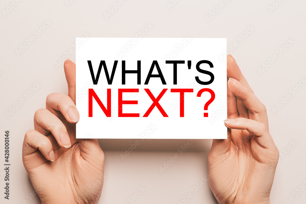 Female hands hold card paper with text what is next on a yellow background. Business and finance concept Female hands hold card paper with text what is next on a yellow background. Business and finance concept