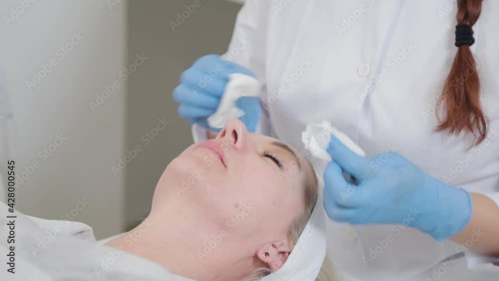 Professional beautician woman washes face to client with napkins. Professional beautician woman washes face to client with napkins.