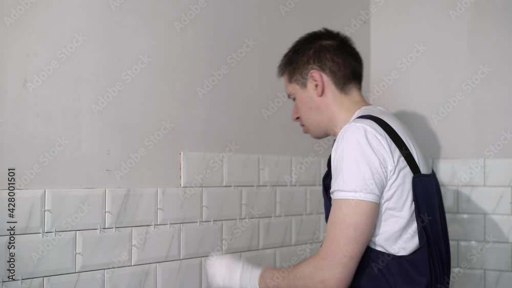 A working builder at the construction site is doing renovation repairs. Laying tile on the wall. High quality 4k footage A working builder at the construction site is doing renovation repairs. Laying tile on the wall. High quality 4k footage