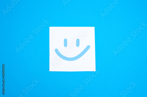 Smile on the white To Do List Sticker. Close up of reminder note paper on the blue background. Copy space. Minimalism, original and creative photo. Positive thinking. All be alright.