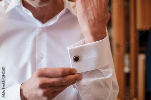 Foto The man fastens the cufflink on the sleeve of his shirt