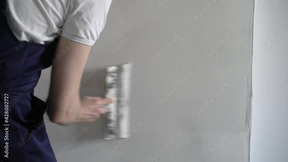 A construction worker builder makes repairs renovation in an apartment or building. Put on a putty, leveling the walls High quality 4k footage