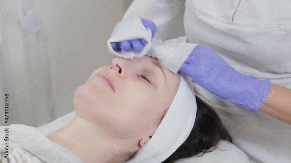 Professional beautician woman washes face to client with napkins. Professional beautician woman washes face to client with napkins.