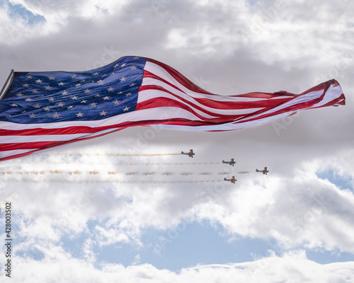 Giant US flag blows in the wind with biplane flyby
