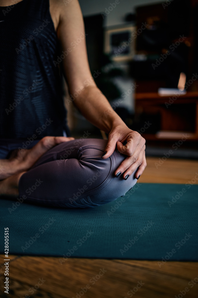 A middle aged woman sitting at home and meditating. Woman doing yoga at home