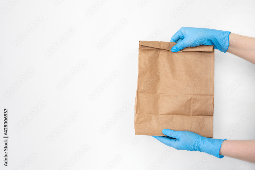 Сoncept of safe home delivery in a pandemic. Coronavirus 2019-nCov Protection. Courier Paper bag hand in medical glove.Copy space .