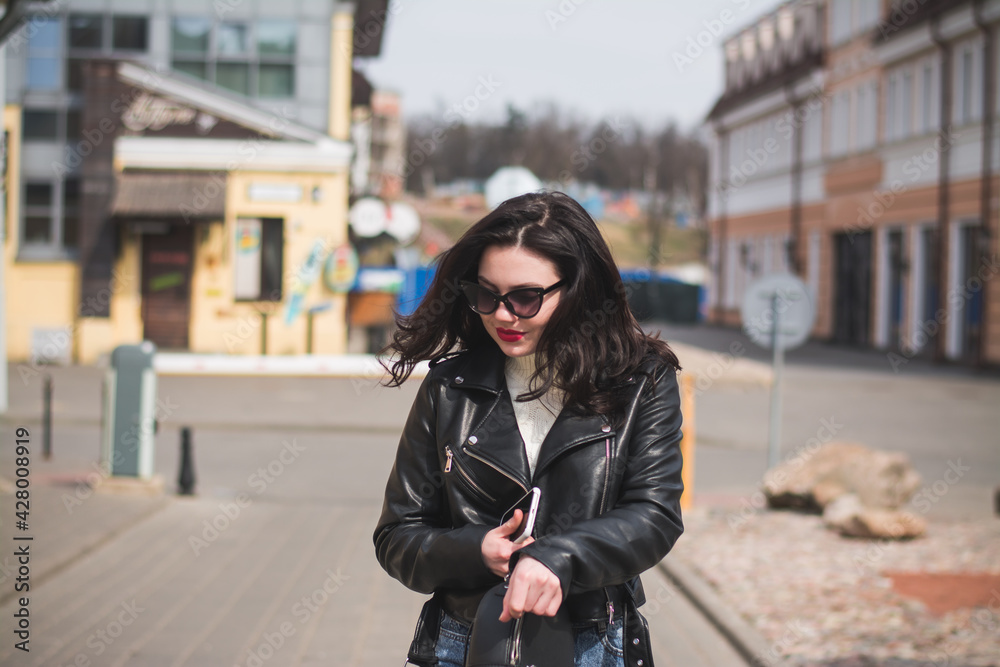 Beautiful young girl student hipster walks along the street of her city Beautiful young girl student hipster walks along the street of her city