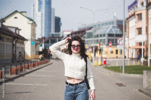 Beautiful young girl student hipster walks along the street of her city