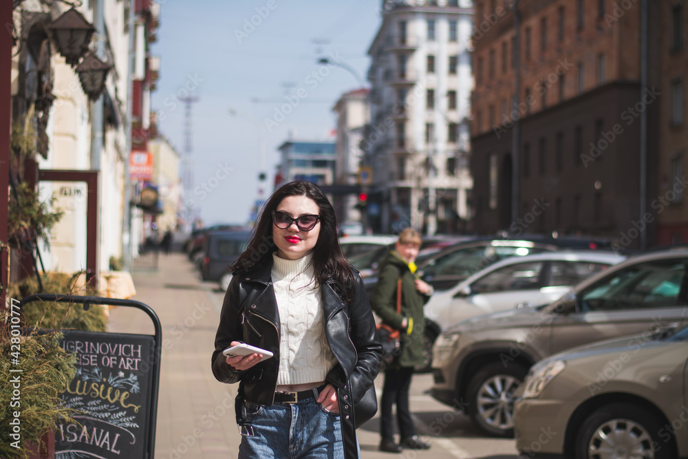 Beautiful young girl student hipster walks along the street of her city
