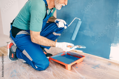 Senior male painter painting a wall. photo