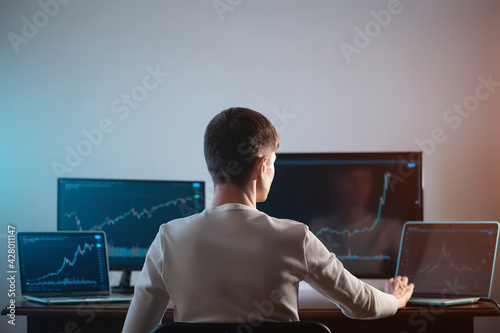 Obraz na plátně back view of male trader looking at monitor with stock exchange graph or chart
