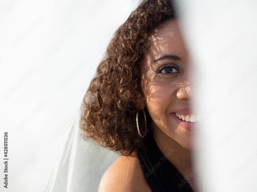 Retrato de persona morena de cabello corto rizado, de Honduras,  Latinoamericana, mirando con una tela blanca tapándo el rostro a medias,  con una sonrisa grande. Primavera de 2021. Stock Photo | Adobe Stock