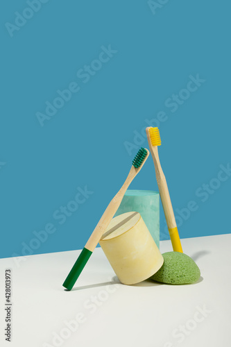 Modern still life.Isometric diagonal projection. geometric yellow shapes, stand. bamboo toothbrush.sponge konjac.Zero waste, pastel blue and pink background. Eco friendly, sustainable lifestyle
