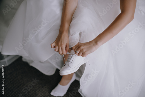 morning of the bride, getting ready, the bride in a wedding dress puts on wedding shoes, legs close-up