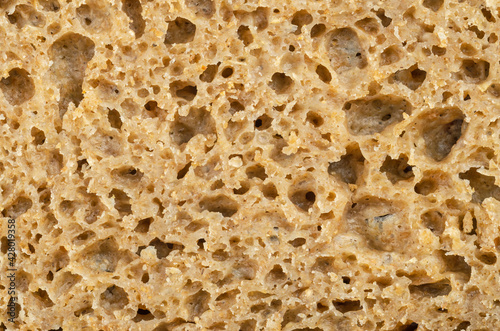 Surface of a fresh cut rye bread, close-up from above. Brown colored sourdough bread, a mix of rye grain flour, leaven and spices, baked in an oven. Staple food. Isolated over white, macro food photo.