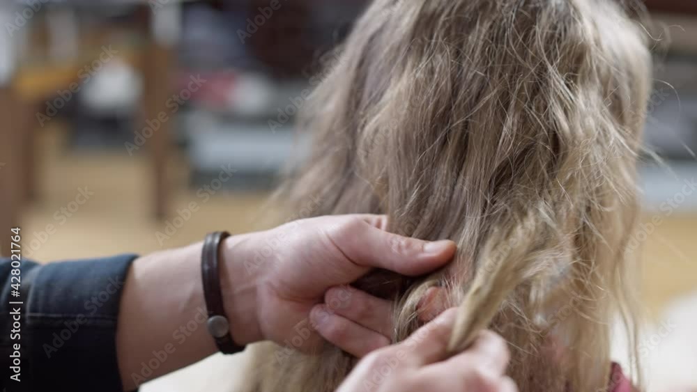 Close-up of male hands trying making pigtail on long curly child's hair. Unrecognizable Caucasian young father taking care of daughter at home indoors. Parenting concept Close-up of male hands trying making pigtail on long curly child's hair. Unrecognizable Caucasian young father taking care of daughter at home indoors. Parenting concept