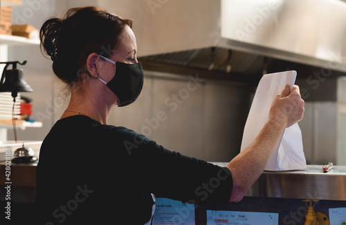 Restaurant employee picking up take out order from a kitchen window