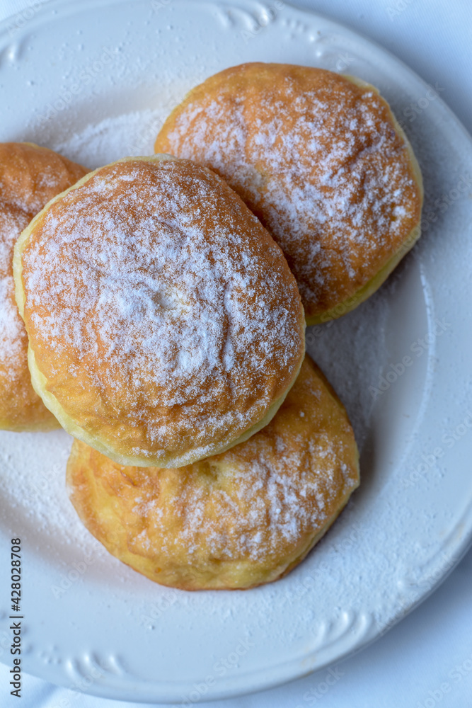 sweet bombolone or Krapfen (or berliner, or doughnut ) made from yeast dough fried, with chocolate curd filling, powdered conventional sugar on top.