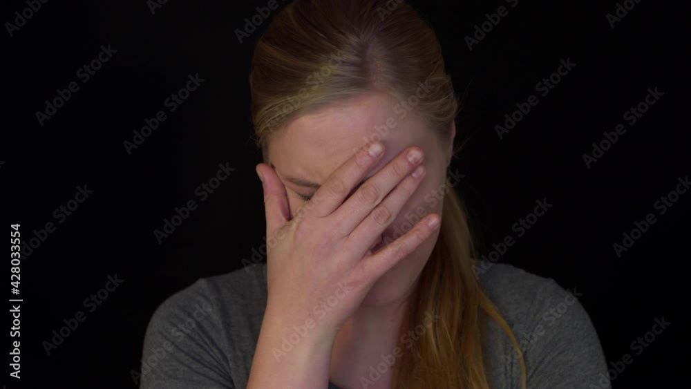Woman in desperation. The slowmotion video with crying woman on black background. She is stressed and despair because on isolation while Covid pandemic.